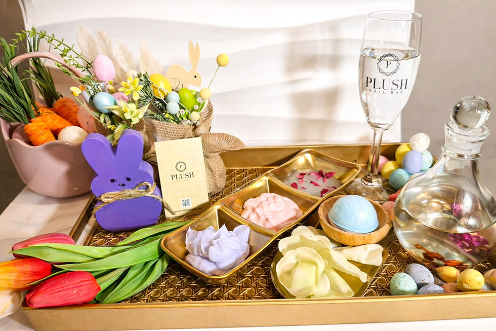 A spring-themed tray with colorful eggs, tulips, a purple bunny, and decorative elements. A Plush Nail Bar glass is filled with water.