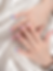 Close-up of hands with glossy pink, blue, and red patterned manicure resting on silky white satin.