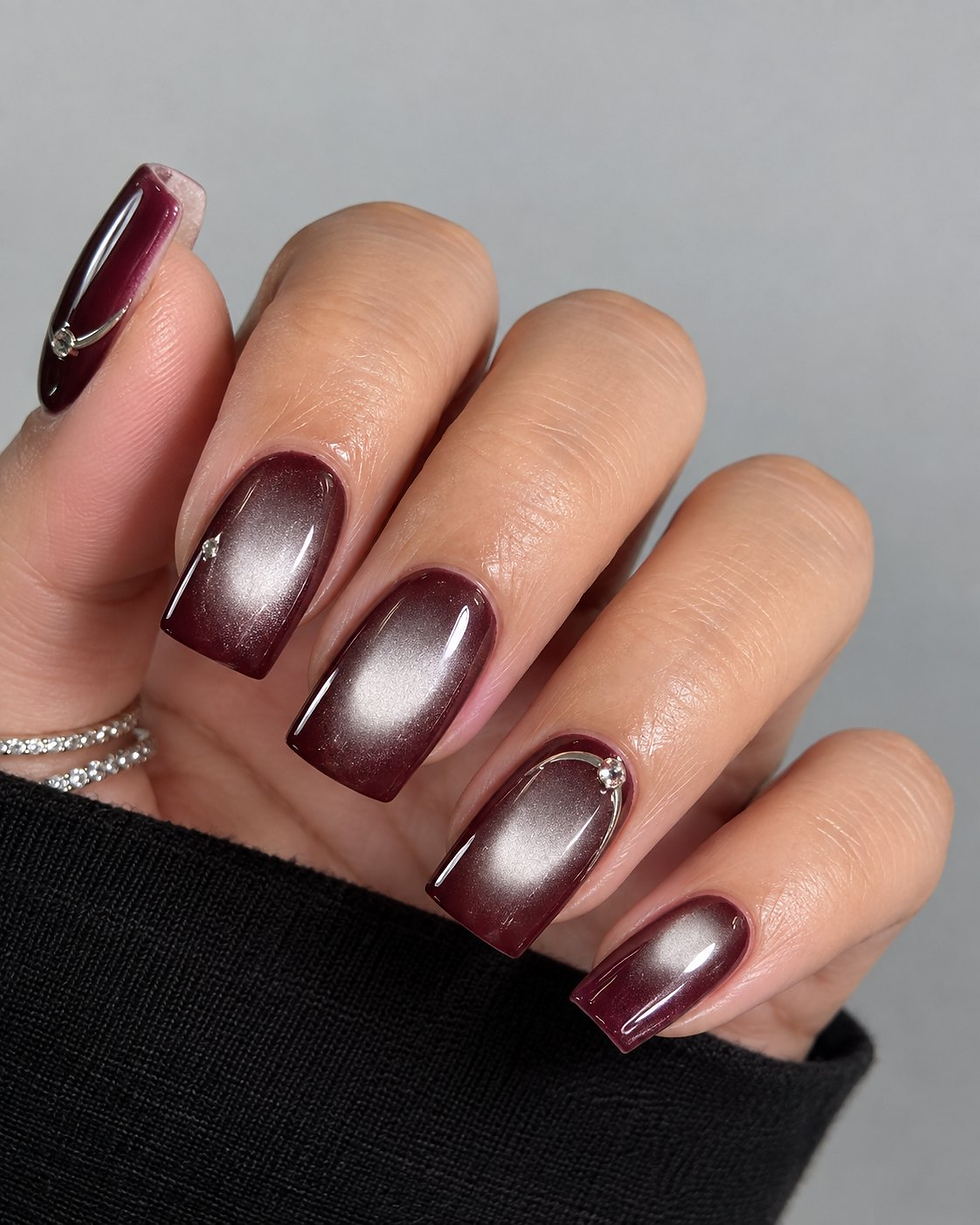 Oxblood cat-eye nails on short square tips with a vertical silver light beam