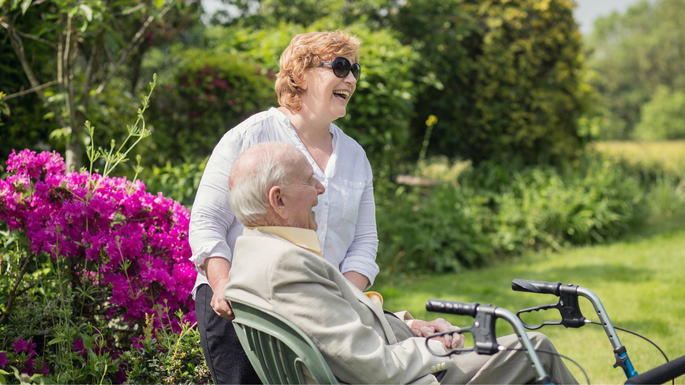 Elderly lady in pretty garden with her home carer drinking cup of tea