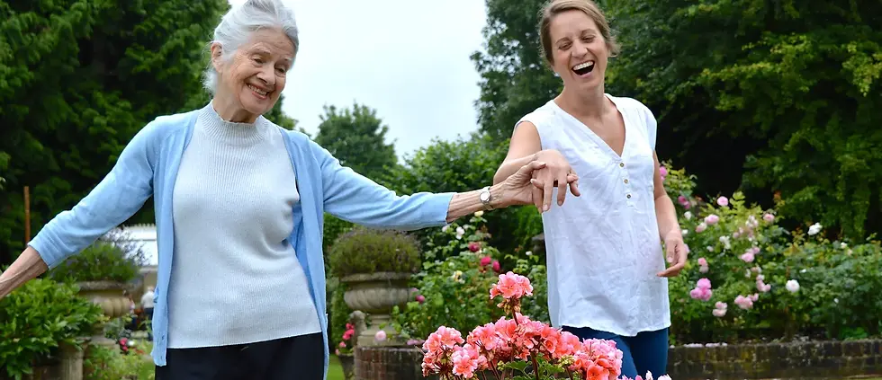 Smiling elderly lady in pretty garden with her one to one carer