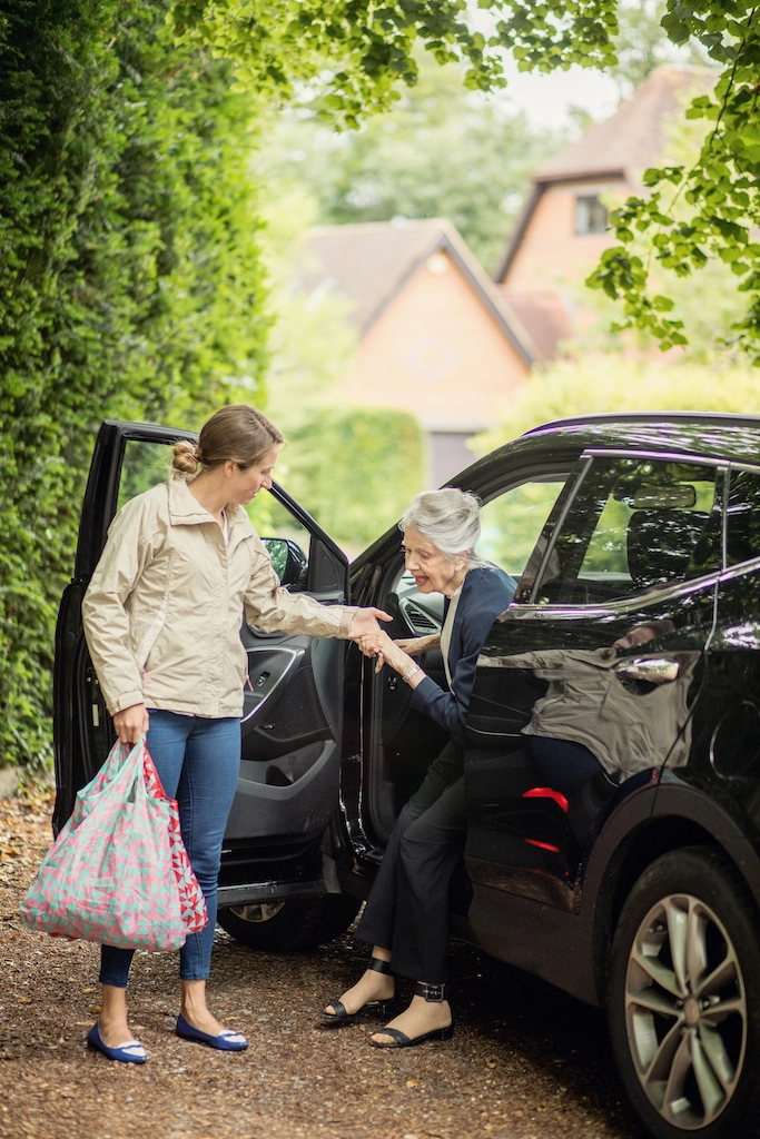 Home carer helping elderly lady out of car with live in elder care