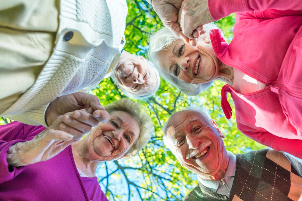 Group of smiling elderly people outside under trees