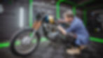 An expert detailer from Lux Lab Detailers meticulously detailing the engine of a classic motorcycle in their Exeter studio, showcasing expert craftsmanship.