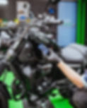 A Lux Lab detailer meticulously applying a Gyeon ceramic coating to the fuel tank of a black motorcycle for long-lasting paint protection in Exeter.