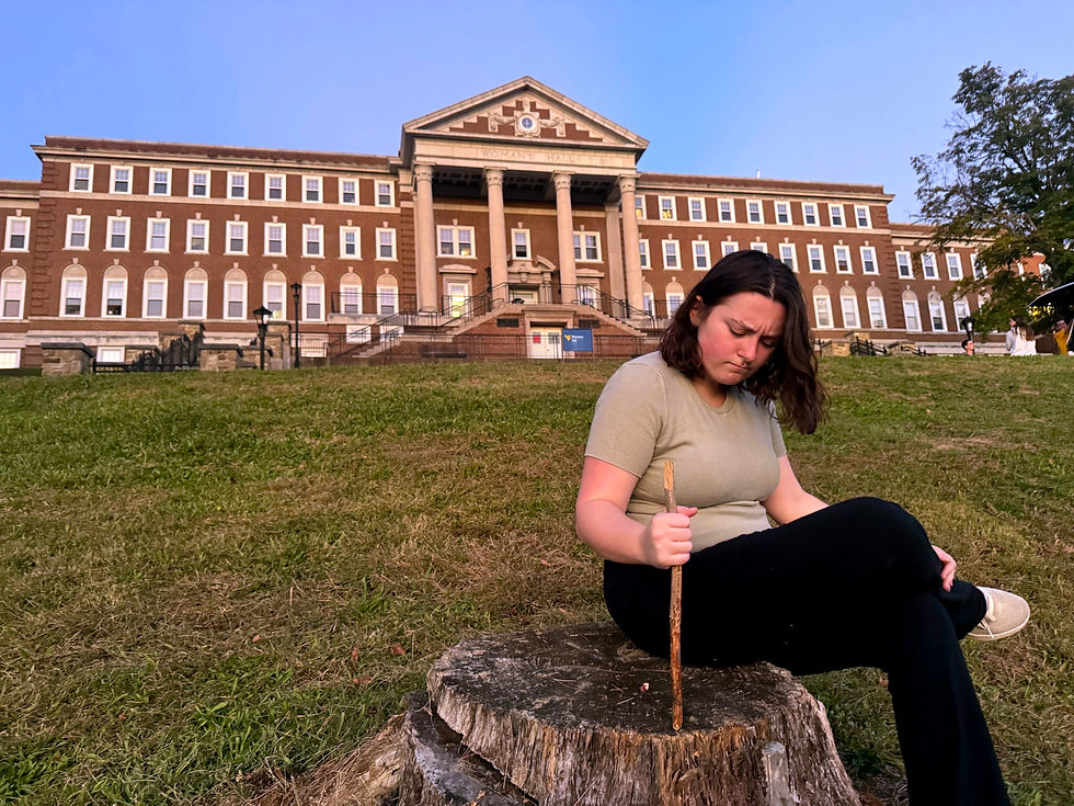Emily Ammer (right) attempting to poke through a tree stump outside of Stalnaker Hall on Friday, Oct. 3, 2025, frustrated that it will not work in her favor.