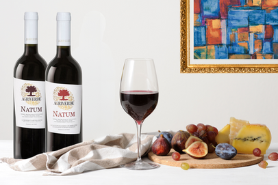 Appetizing wine glass, a tray of fruits and cheese and two bottles of italian red wines