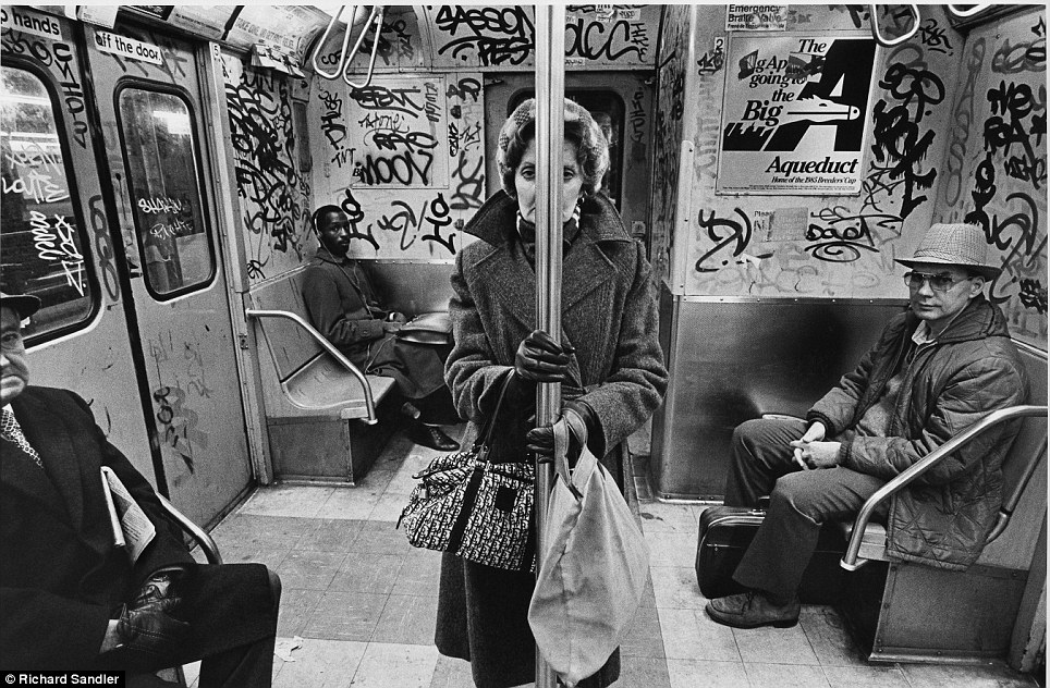 Training day- A woman stands in the graffiti-covered carriage of the C train in 1985 as other commut