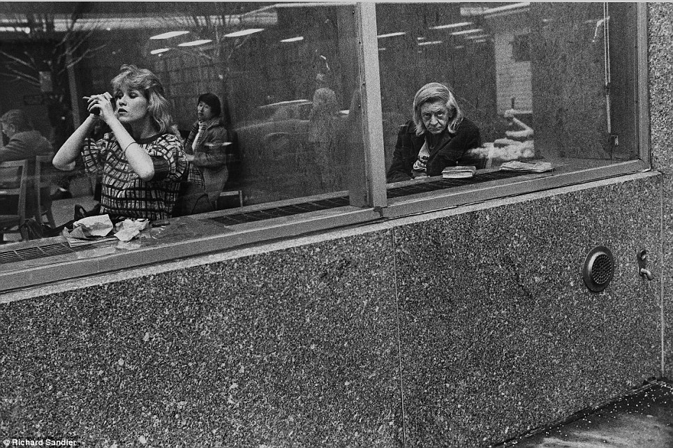 he stare- A woman applies make-up as she sits in the window of the Donnell Library in 1981 while ano