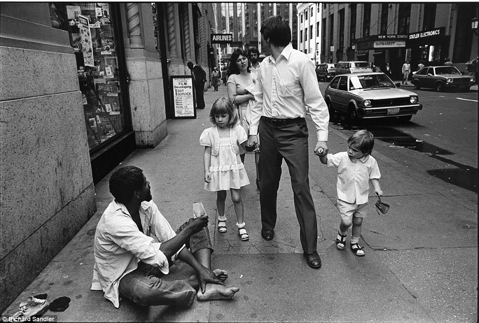 New York state of mind- Two children stare curiously at a homeless man as they walk with their paren