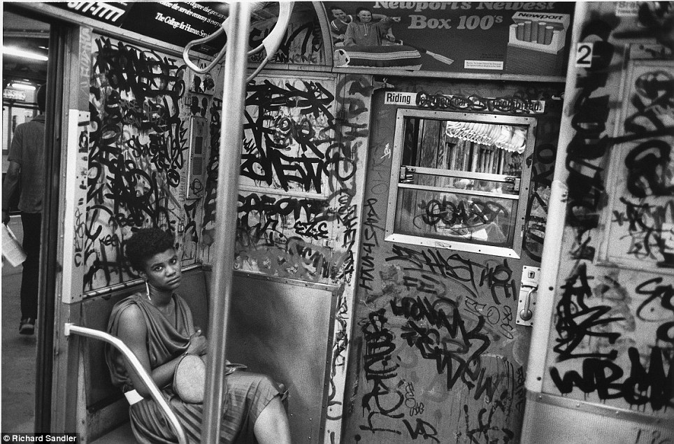 Tagged- A woman looks up from a subway car so covered in graffiti it's almost more paint than wall i