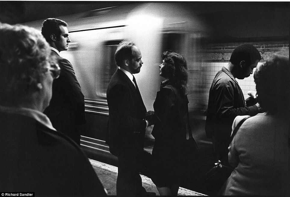 Platform love- A couple surrounded canoodles on a busy subway platform as a train rushes by in 1985