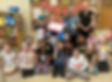 Group of children in a classroom smiling and holding a donation cheque