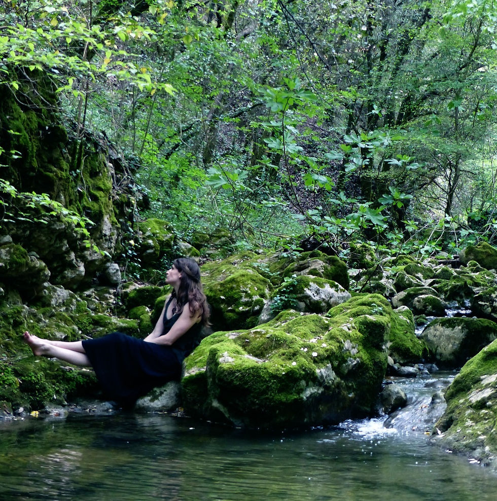 Une femme est assise près d'une cascade luxuriante.