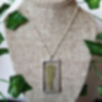 A necklace with a stained glass pendant containing a pressed fern