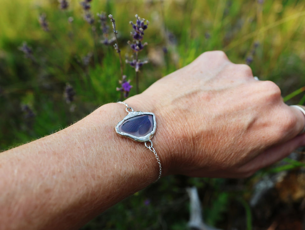 A stained glass bracelet showcasing a real pair of damselfly wings on a woman's wrist in nature