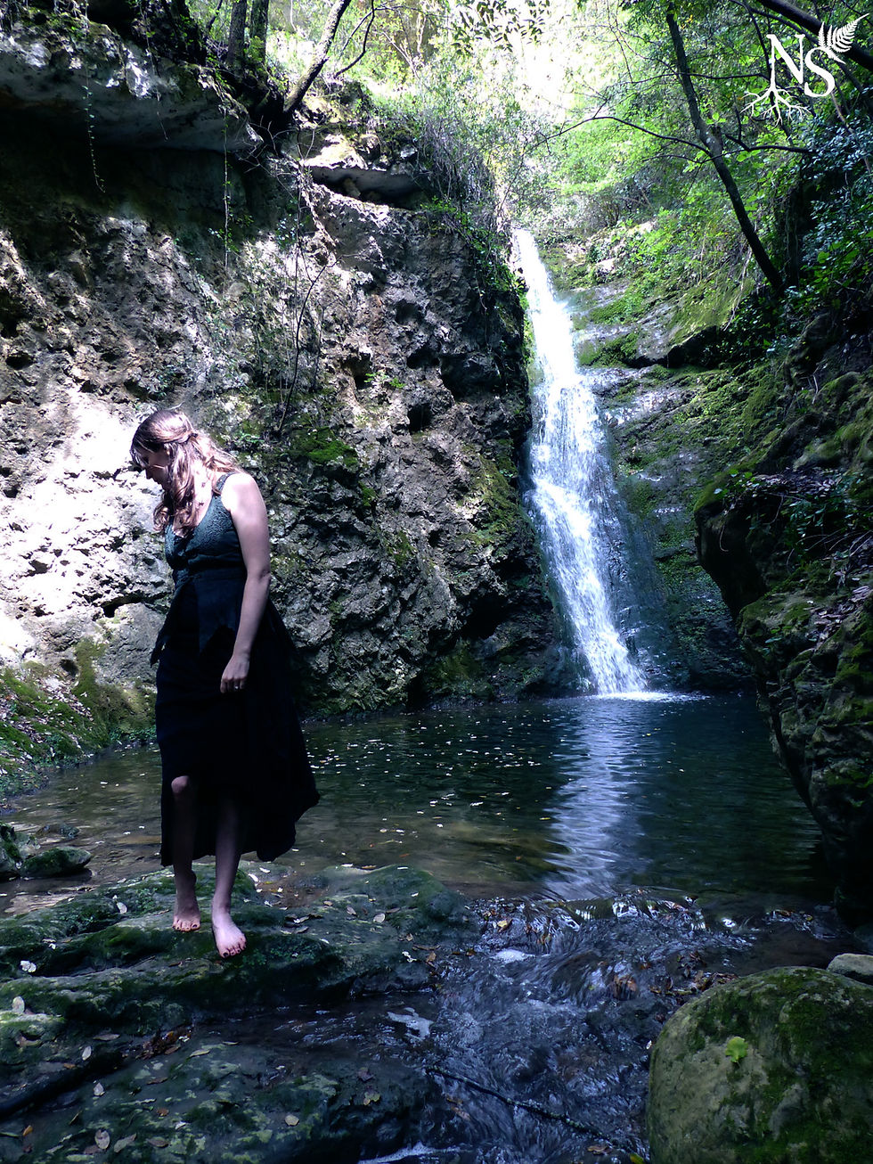 A woman is standing near a secret waterfall.
