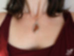 a woman's neckline with a necklace. The pendant is a stained glass pendant with real insects wings inside.