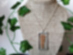 A necklace with a stained glass pendant containing a pressed fern