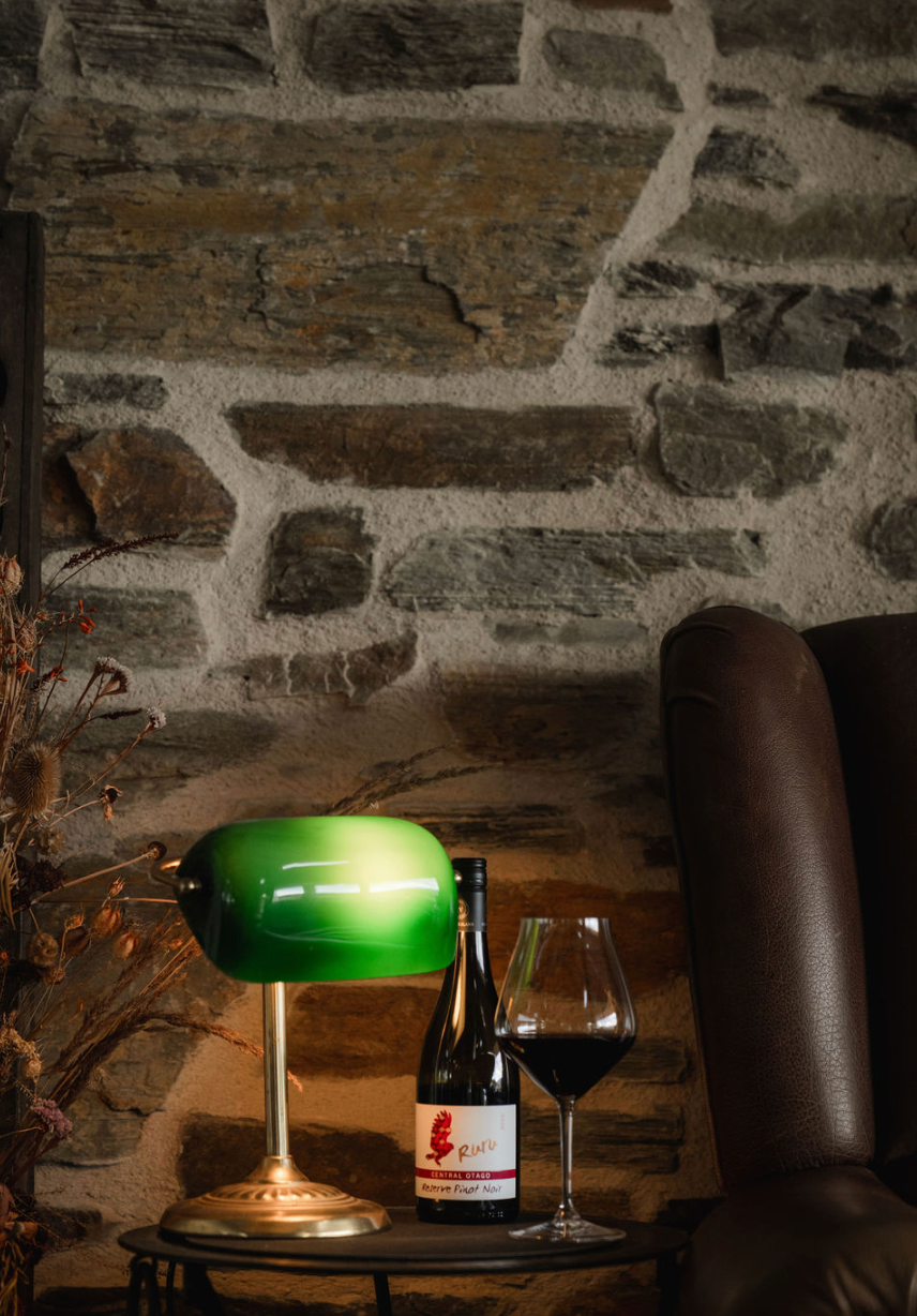 Cozy setting with lamp, wine bottle, and glass.