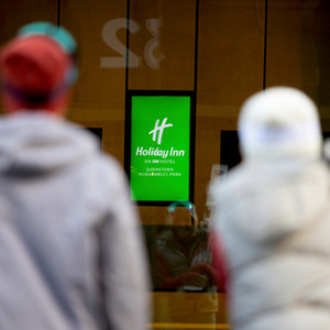 Two people facing Holiday Inn sign.