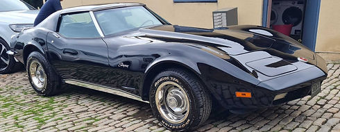 black vintage sports car is parked on a cobblestone driveway