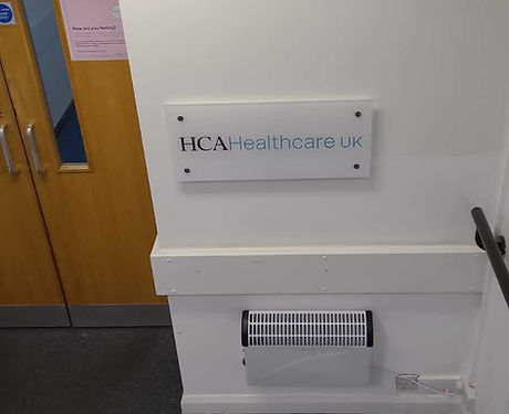 The front door to HCA Healthcare UK offices, complete with white sign stating the company name nailed to the wall.
