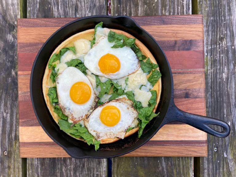dutch baby pancake in cast iron skillet with fried eggs on top
