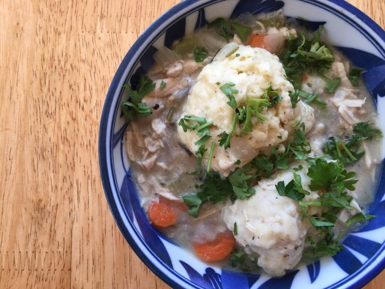 chicken and dumplings soup in a blue and white bowl