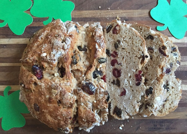 Irish soda bread loaf with paper shamrocks beside it.