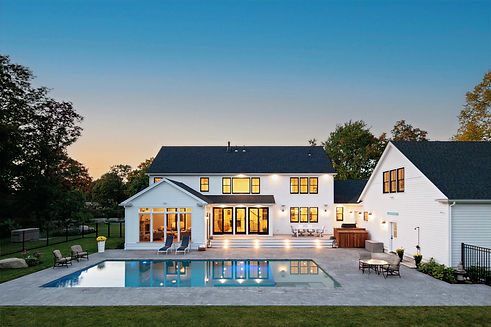 Modern white home with backyard pool and illuminated windows