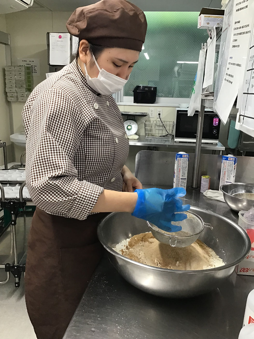 ボールで粉をふるう国立クムクム保育園で栄養士として活躍する岡先生。