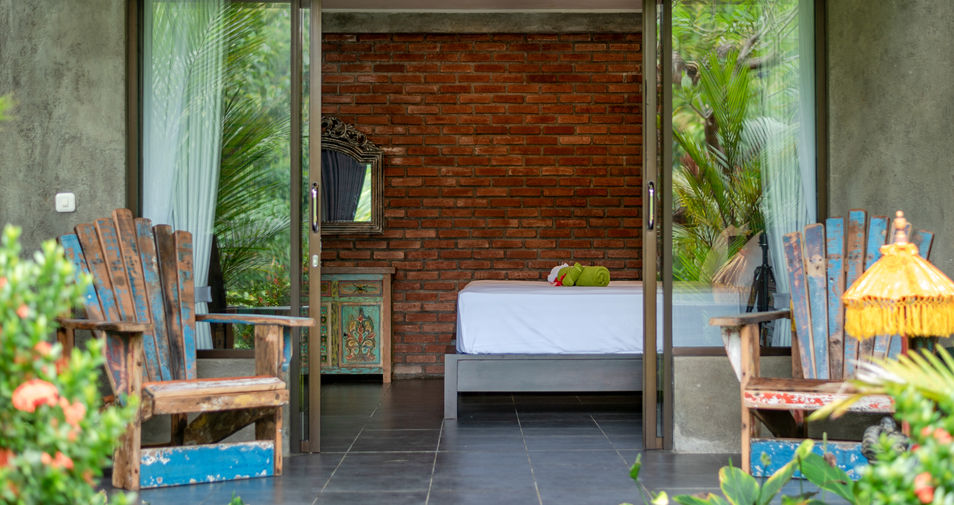 Room with chairs, brick wall, and bed