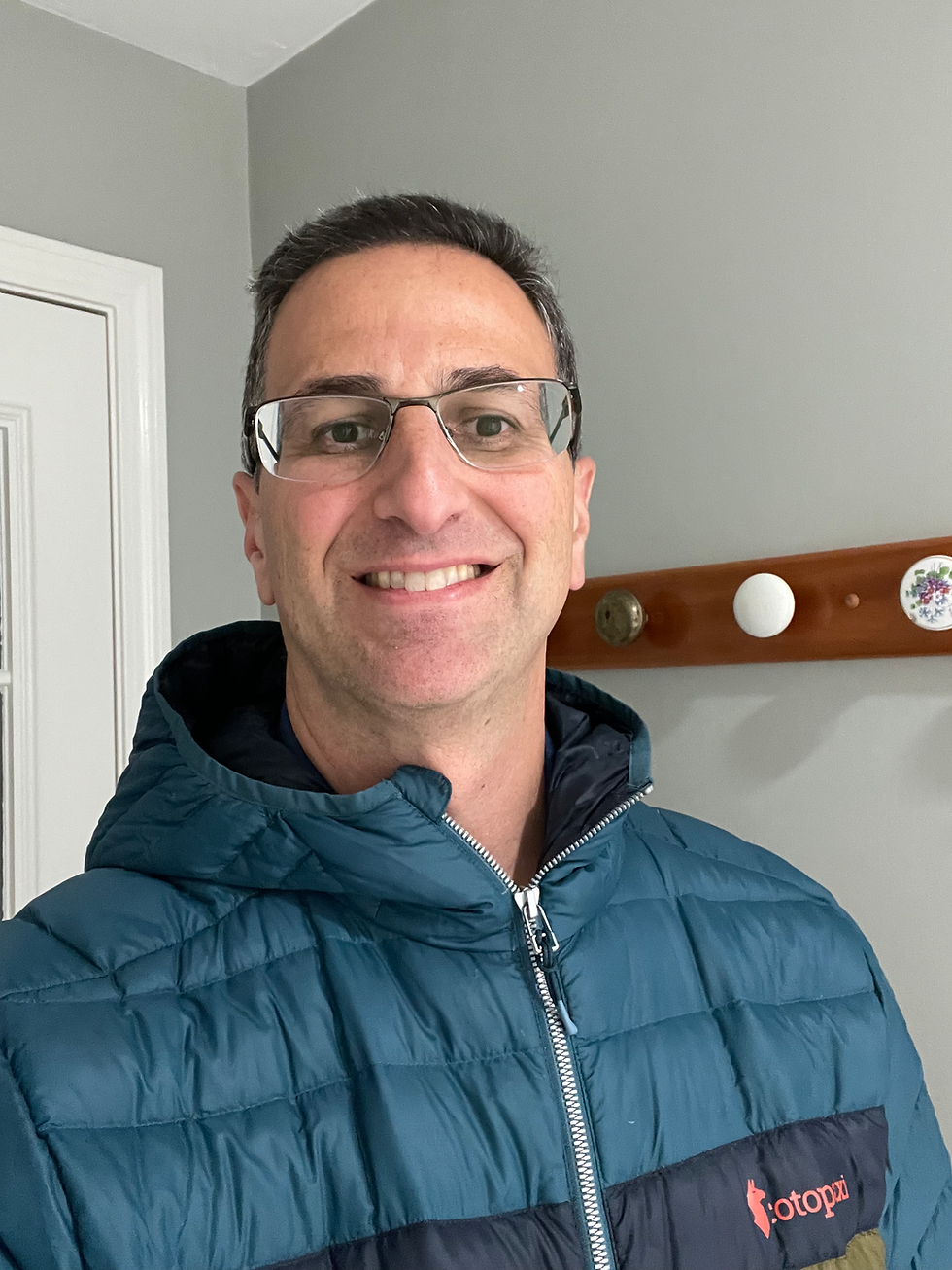 Man in glasses smiling in a blue Cotopaxi Fuego jacket Luminous blue Cotopaxi Fuego jacket worn by Steve for Rooted & Refined Living, showcasing a textured, high-end winter style.