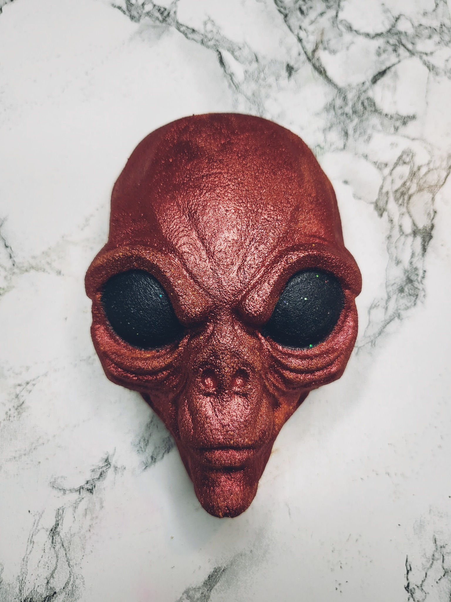 bath bomb in the shape of a red alien head with black eyes