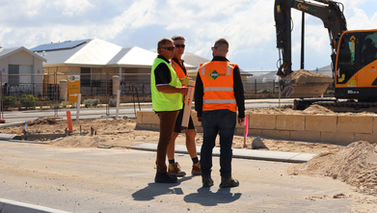 A trio of men discuss plans for a residential estate whilst assessing works.