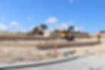 Construction vehicles levelling sand on a subdivision development.