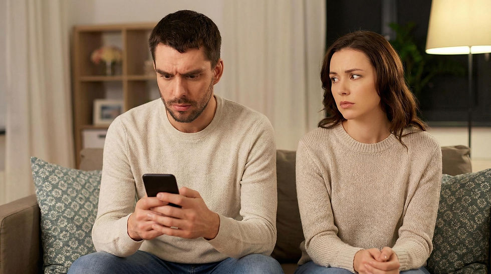 Deux adultes en couple sont assis sur un canapé, dans une atmosphère tendue. L'un tient un téléphone tandis que l'autre semble préoccupé. La scène évoque les difficultés de confiance, les demandes de réassurance et le contrôle dans le couple.