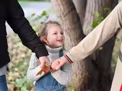 Enfant entouré de deux adultes illustrant la protection, l'écoute et la sécurité affective au sein de la famille.