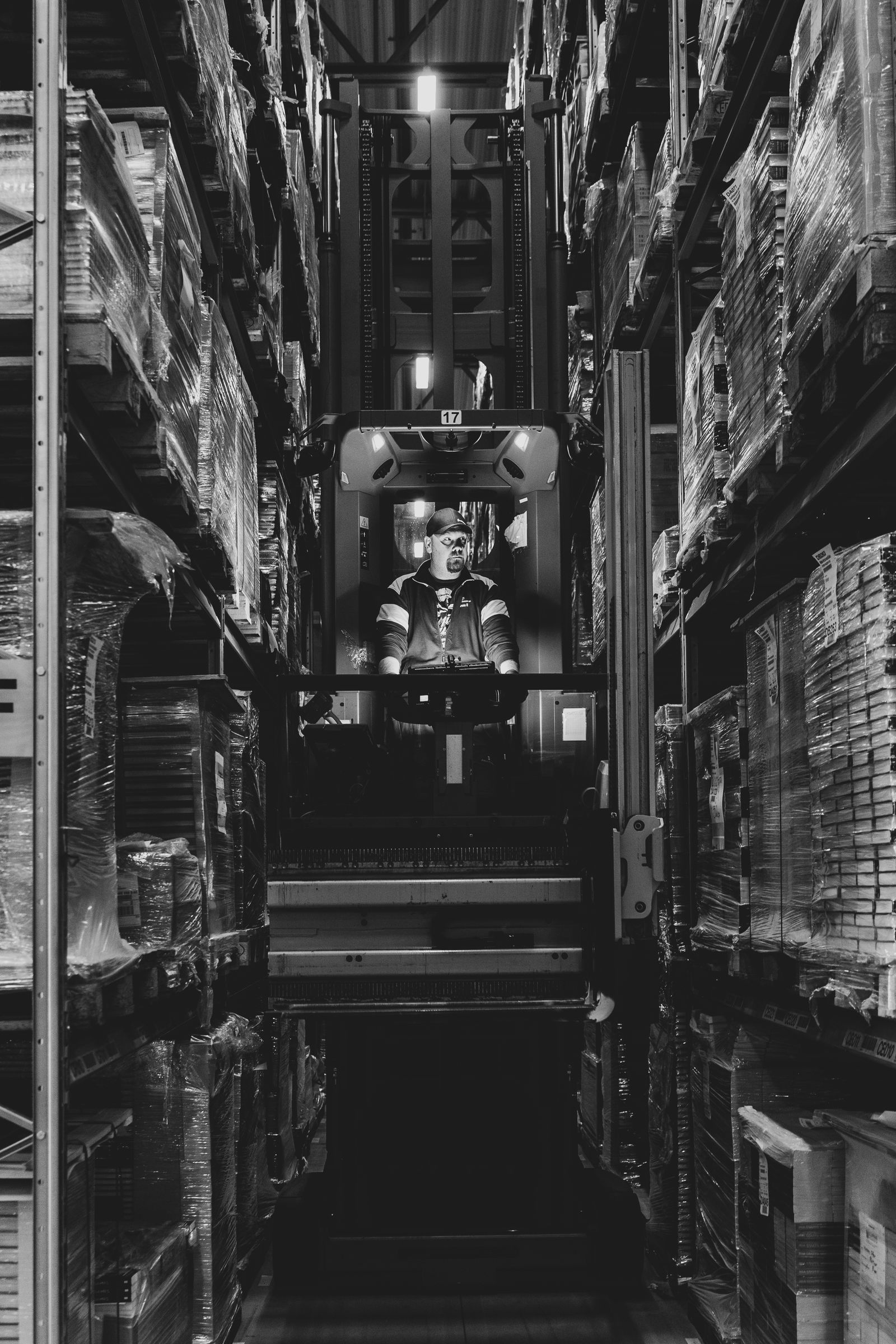Forklift working in a narrow warehouse aisle between tall shelves of packaged goods