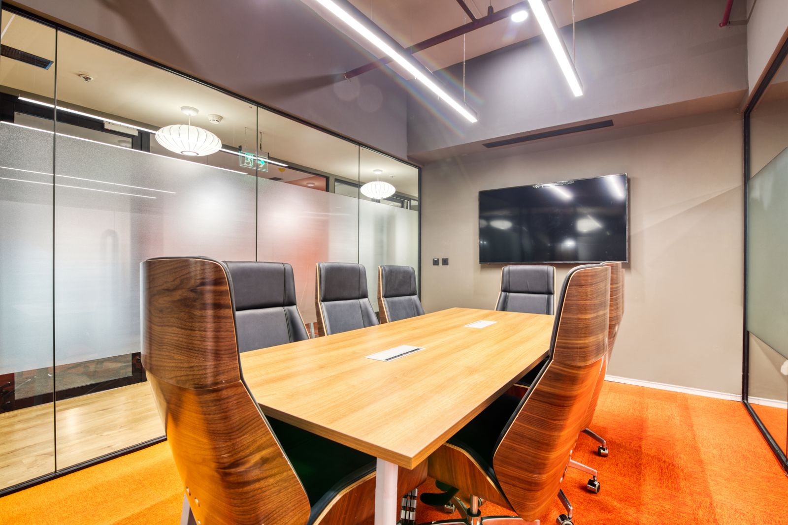 Meeting room with glass walls, a timber table and black office chairs