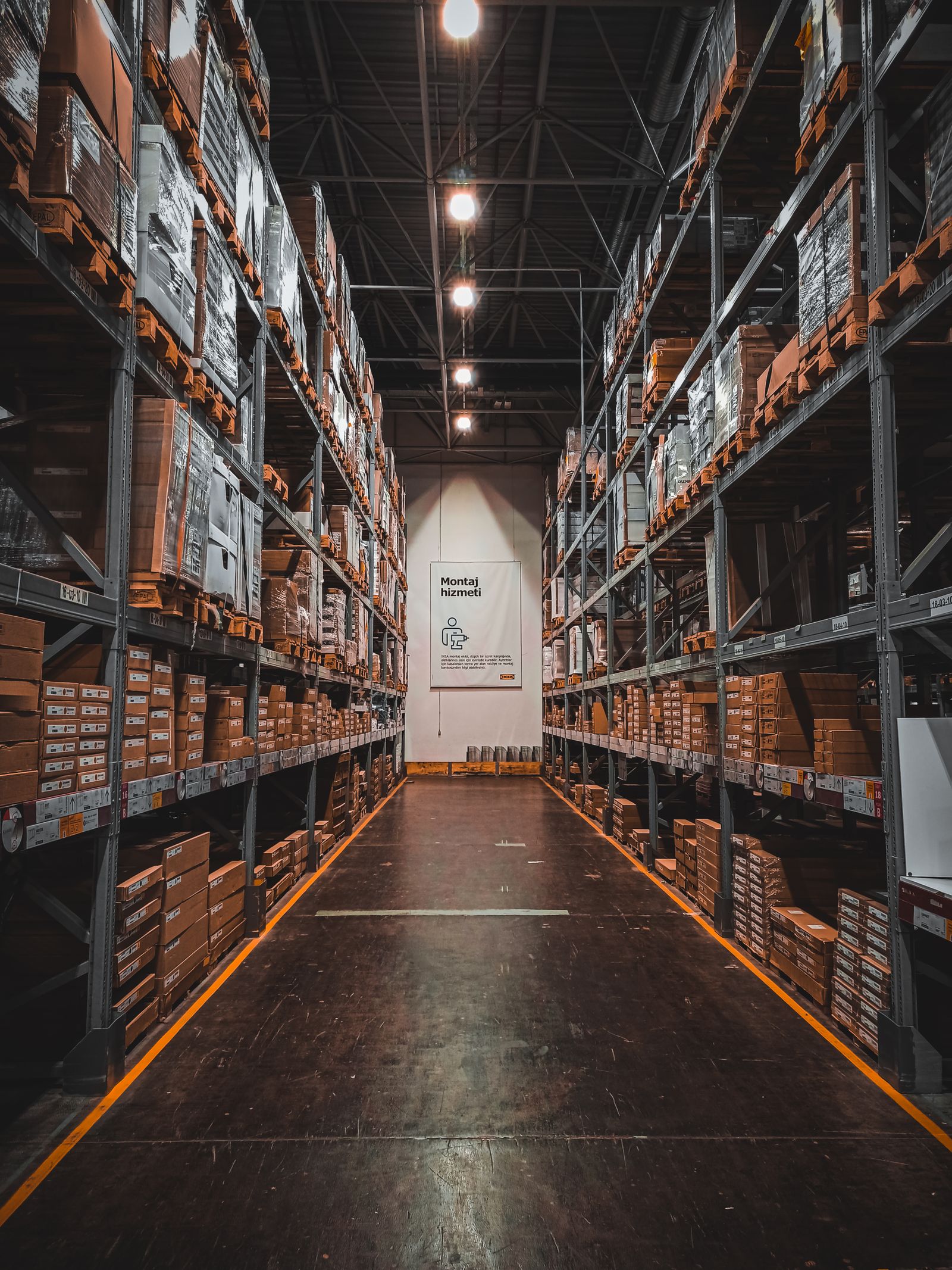 Long warehouse aisle lined with high racking stacked with boxes
