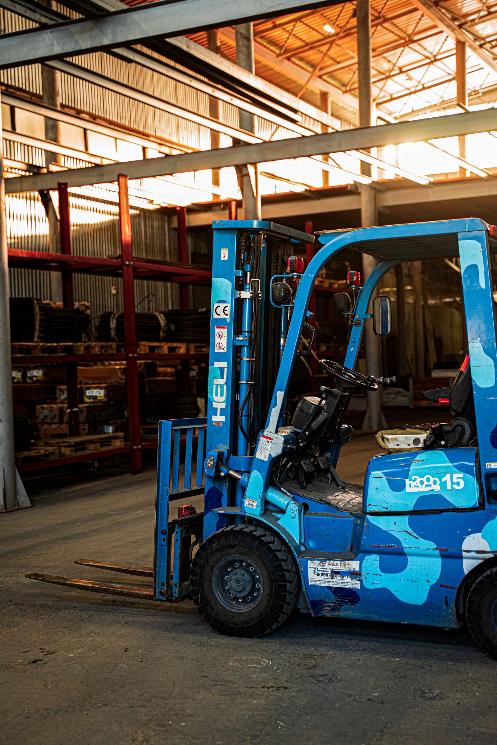 Blue forklift parked beside metal racking inside an industrial warehouse