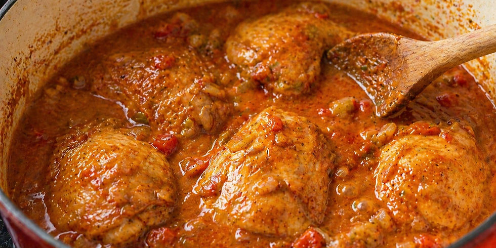 Chicken thighs simmering in a rich, red tomato sauce with spices in a pot. A wooden spoon stirs the sauce, creating a savory aroma.