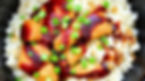 Chicken pieces with brown sauce and green onions on white rice, creating a colorful and appetizing meal in a black bowl.