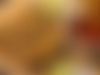 Crispy tacos with shredded meat and cilantro on a wooden board, one being dipped in red sauce. Lime wedges and radish slices nearby.