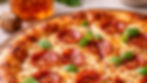 Close-up of a pepperoni pizza with fresh basil, melty cheese, and golden crust. A jar of honey and dipper in the background. Inviting and delicious.