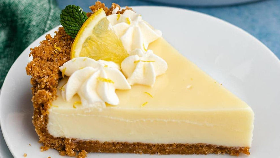 Slice of lemon pie with whipped cream, lemon wedge, and mint on a white plate. Crumbly crust and blue background evoke a fresh mood.