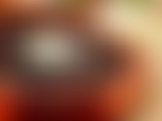 Black bean soup in an orange bowl topped with cheese, next to golden arepas on a colorful striped cloth, creating a cozy, rustic feel.