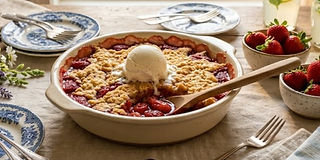Warm strawberry cobbler topped with vanilla ice cream in a baking dish
